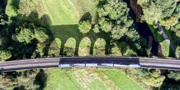 Train pictured from above going through green landscape